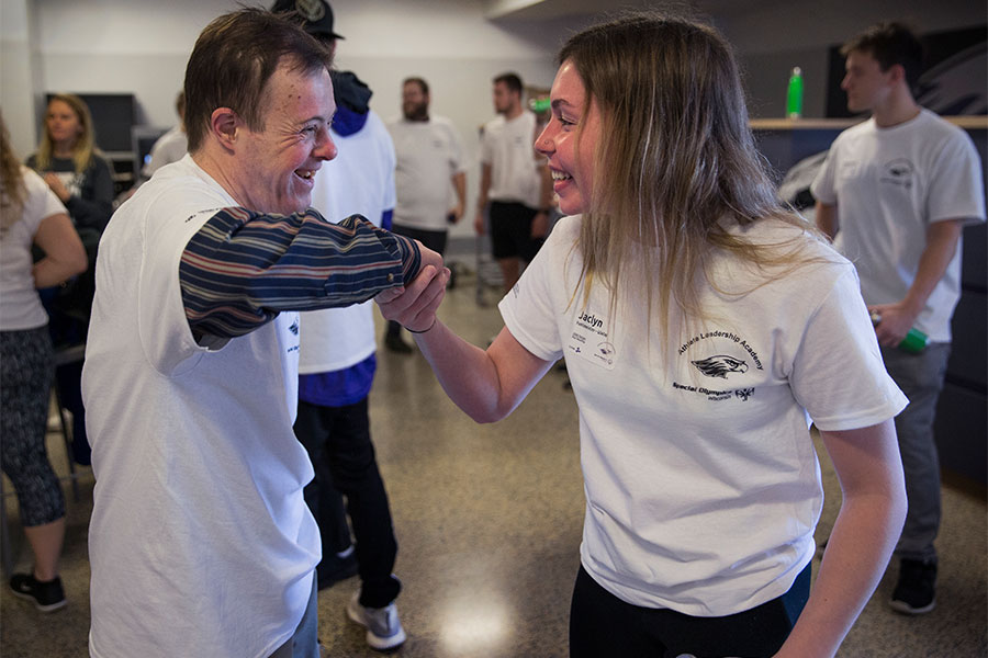 A UW-Whitewater student and a person with a disability smile at each other.