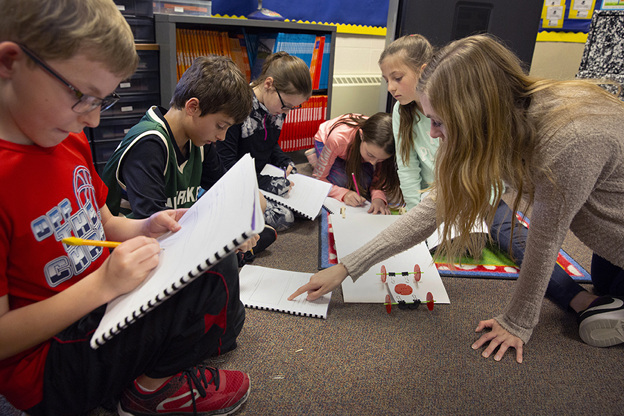 UW-Whitewater student Alexis Kyano helps elementary school students assemble a vehicle  to use in a physics exercise.