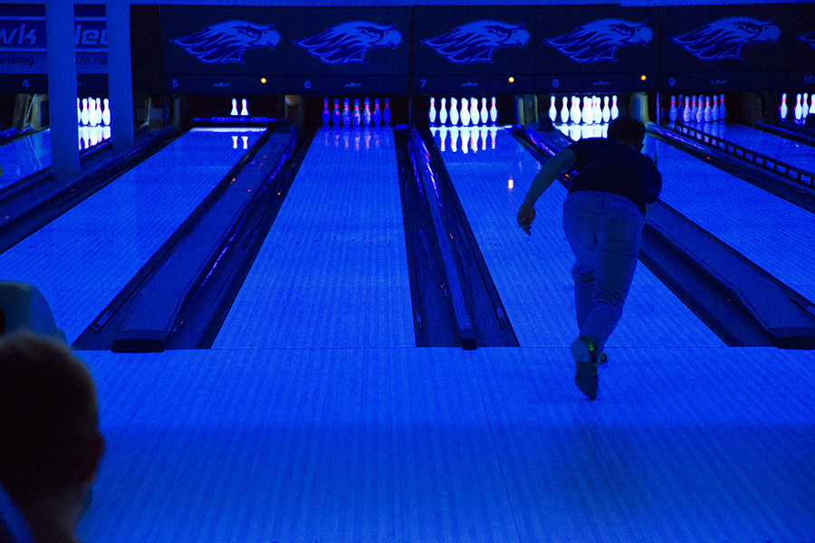 Student bowling in the bowling alley with the blacklights on.