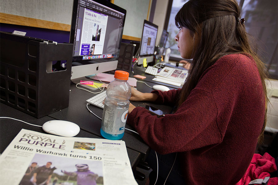 Student works on a computer for The Royal Purple.
