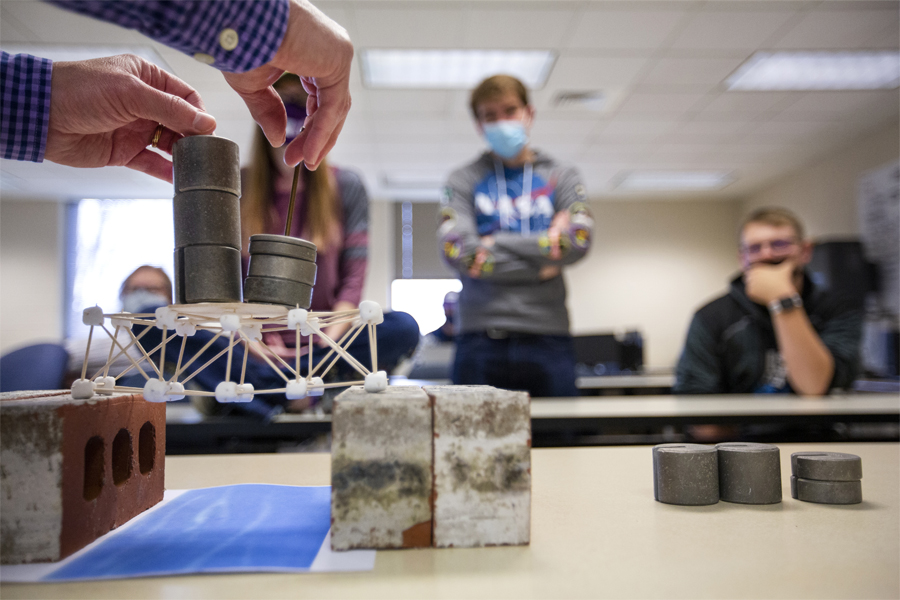 A class builds a bridge demonstration out of weights and toothpicks.