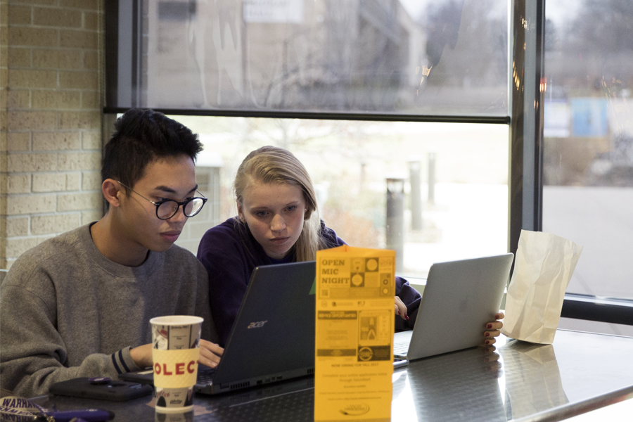 Two students work on a laptop by a window in the University Center.