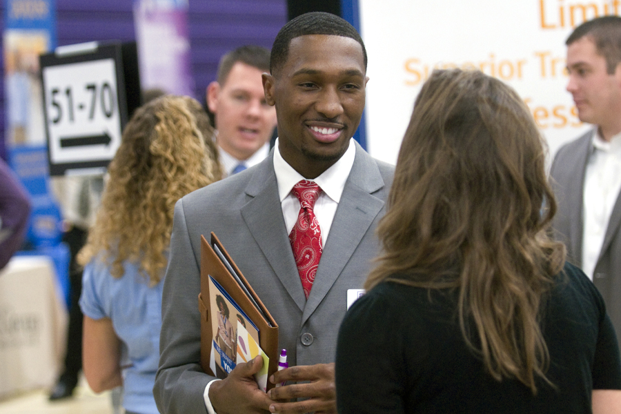 A young student wearing a suit and tie mingles at a career fair.