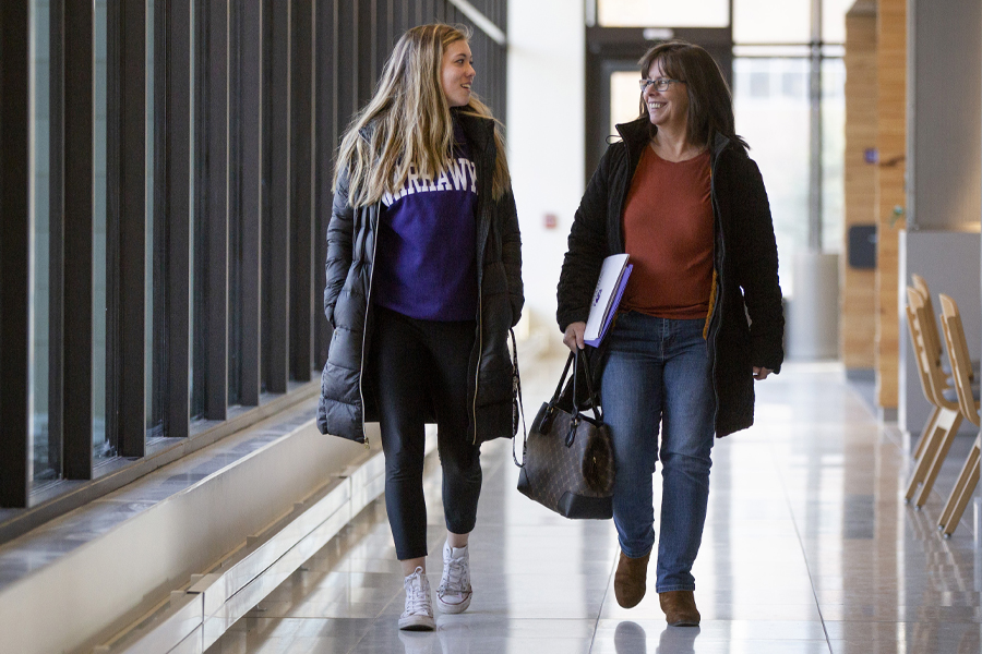 A student walks down a hallway with her mother.