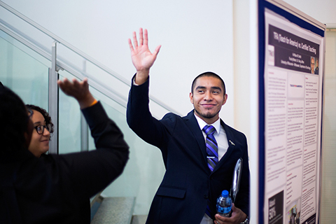 Finance student Miguel Miranda gets a high five from fellow McNair Scholar Jazmin Wilson, near his undergraduate research project on minority banks.