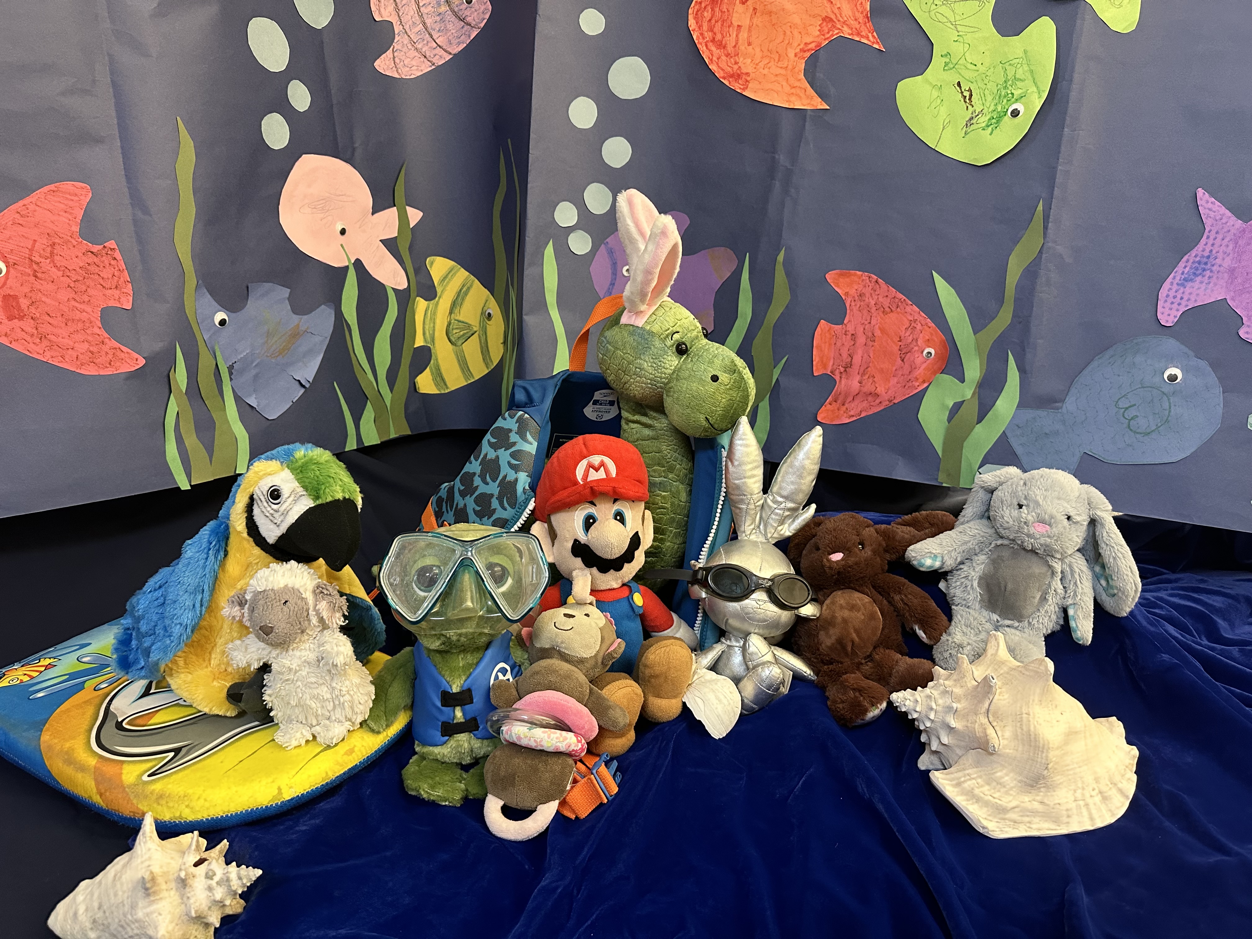 Stuffed animals with backdrop of fish mural made by participants