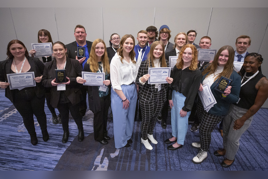 Student broadcasters stand in a group holding awards.
