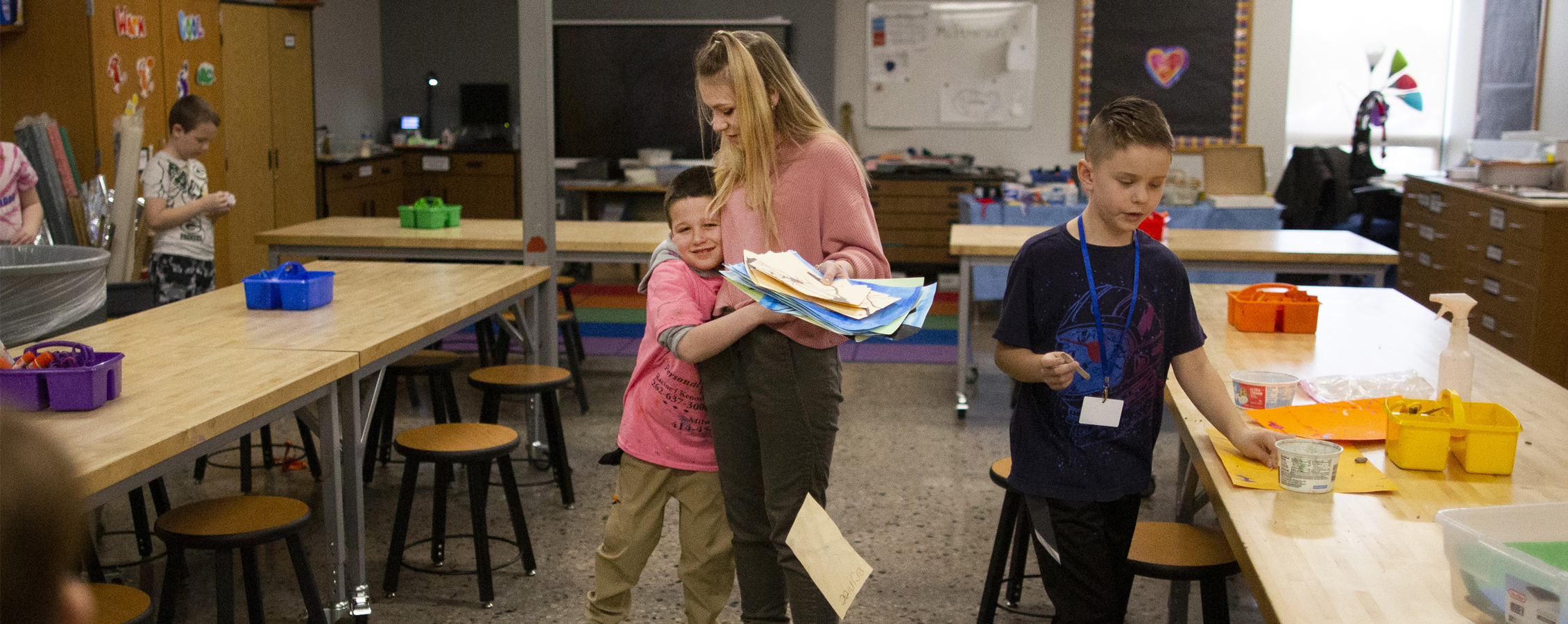 Hollyn Peterson receives a hug from a student in an art classroom.