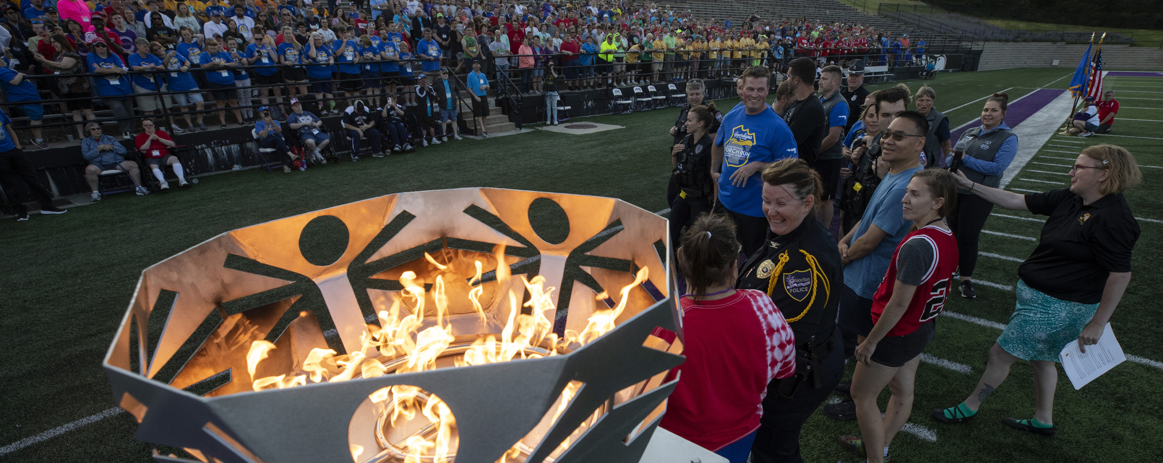 People gather in Perkins Stadium for the opening ceremonies with a fire burning in the cauldron.