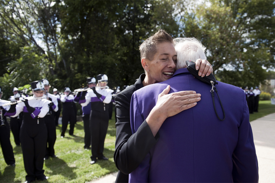 Two people hug while the Marching Band plays behind them.