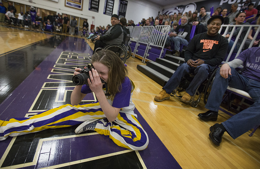 Melanie Juette, left, wears the UW-Whitewater men's wheelchair basketball uniform worn by her father Melvin Juette, behind her at right, when he played for the Warhawks in the early 1990s.