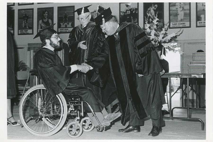 A black and white photo of Chancellor James R. Connor congratulating a student at commencement.