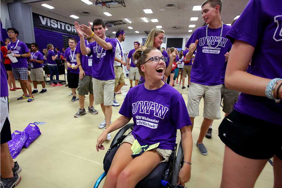 Students, including a student in a wheelchair, celebrate in the gym.