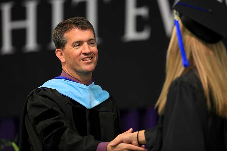 John Chenoweth shakes hands at commencement.