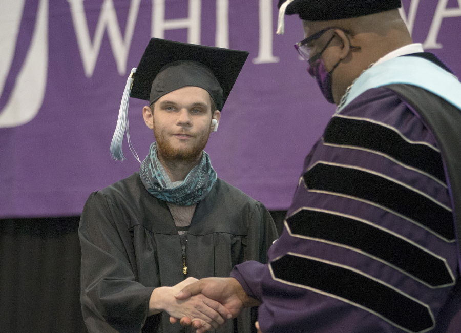 LIFE program participant Sam Craden shakes hands with Chancellor Watson in graduation cap and gown.