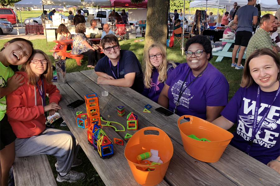 UW-Whitewater LIFE students sit on a picnic bench outside at the Whitewater City market.