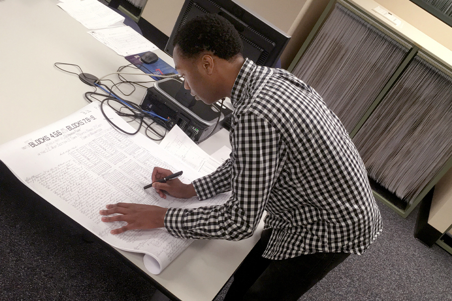 Donovan Hemphill tracing the land genealogy at a desk.