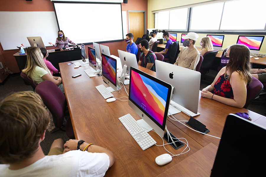 Students sit in class with Mac computers.