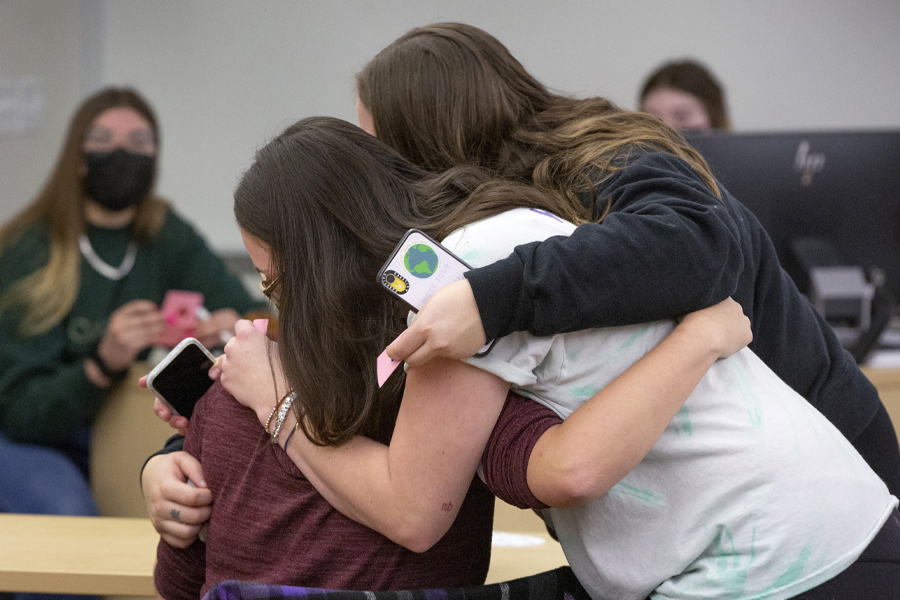 Three people hug.