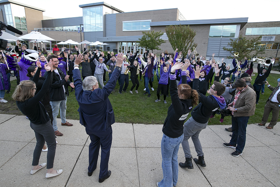 Davin Stavroplos participates with other people outside, standing in a circle, celebrating and clapping.