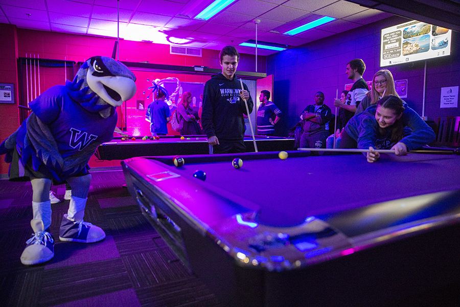Willie Warhawk playing pool with students.