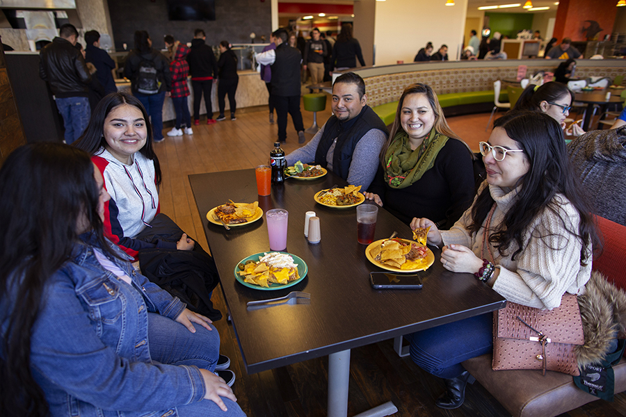 una familia hispana come en un comedor universitario.