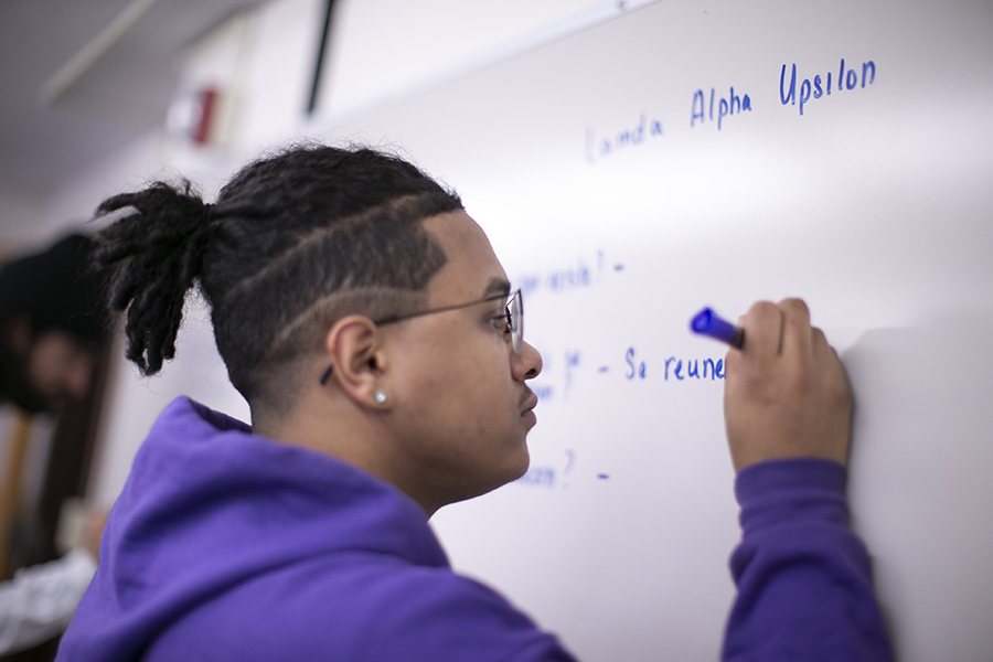 un estudiante masculino escribe en español en una pizarra.