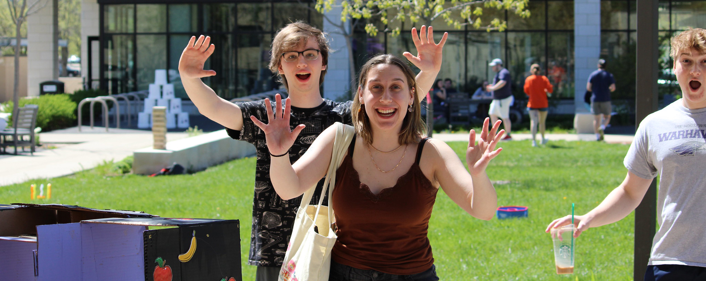Three people are outside with their arms raised and smiling at the camera.