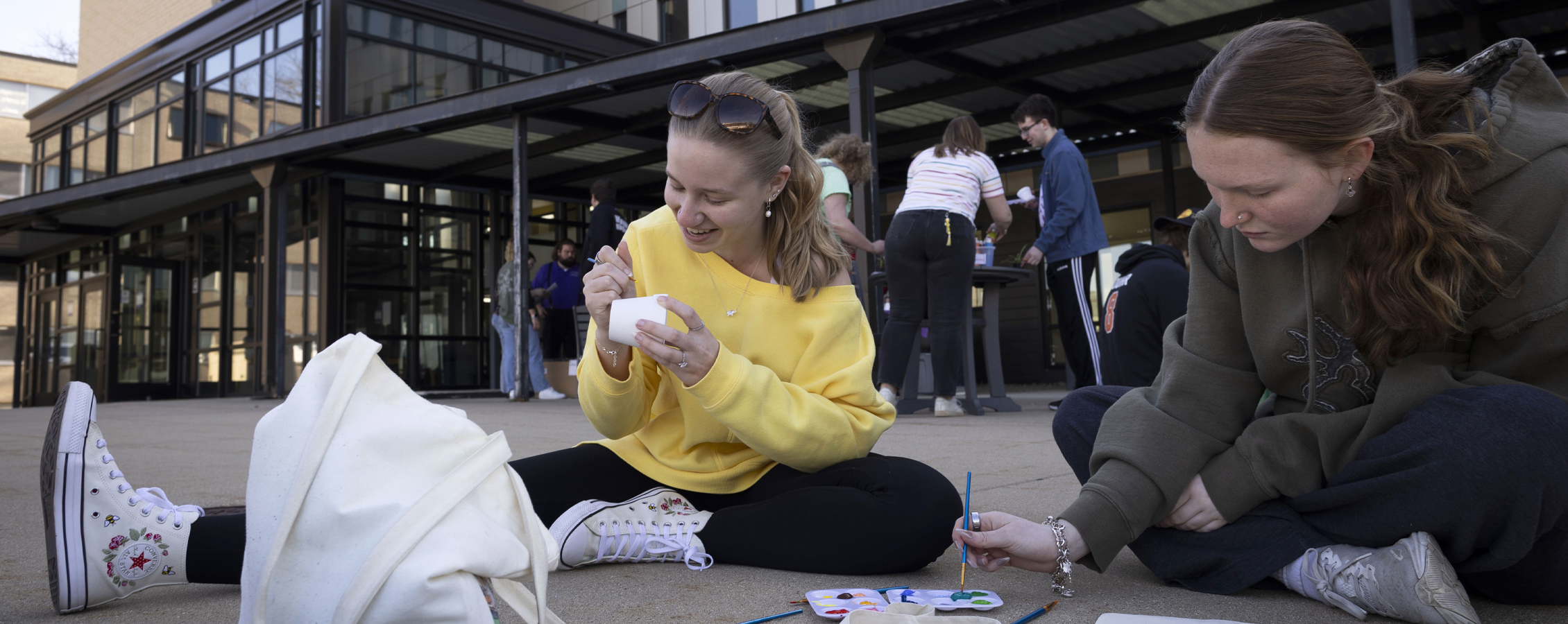 Two students work on an art project outside of the residence halls.