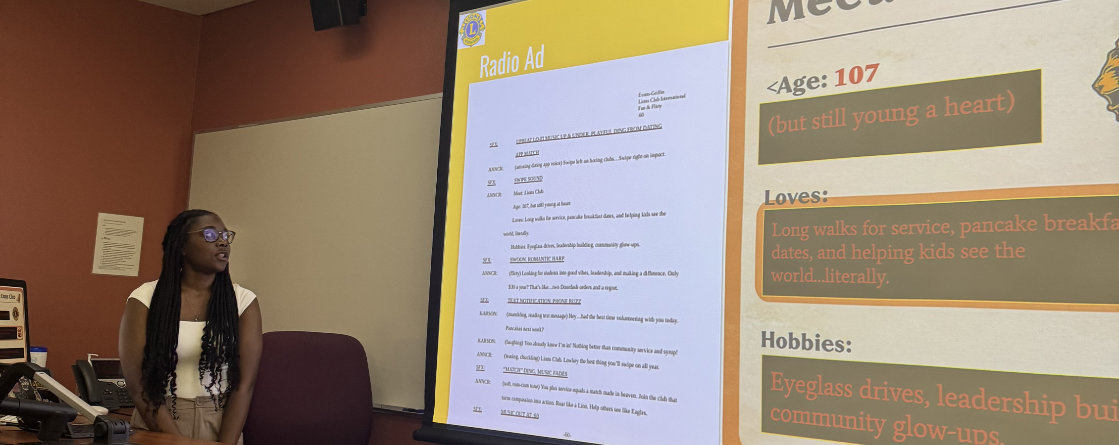 A student stands beside a projection screen and presents work.