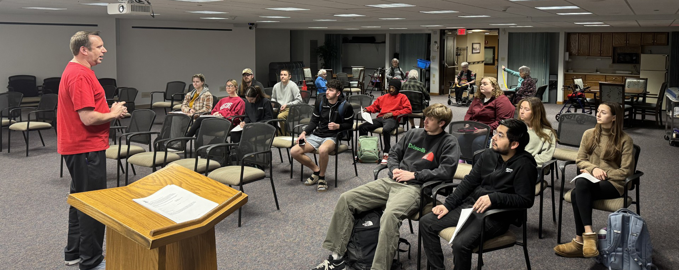A person speaks to a seated crowd.