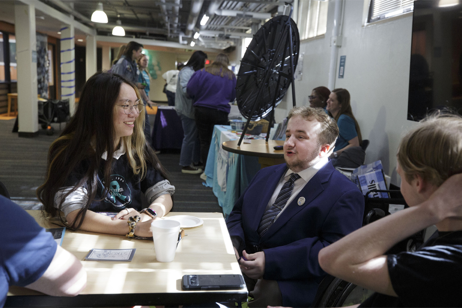 Students talk while sitting at a table.
