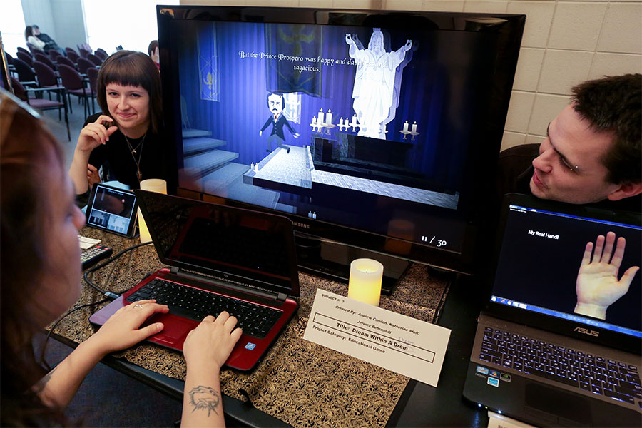 Three students gather around several monitors. 