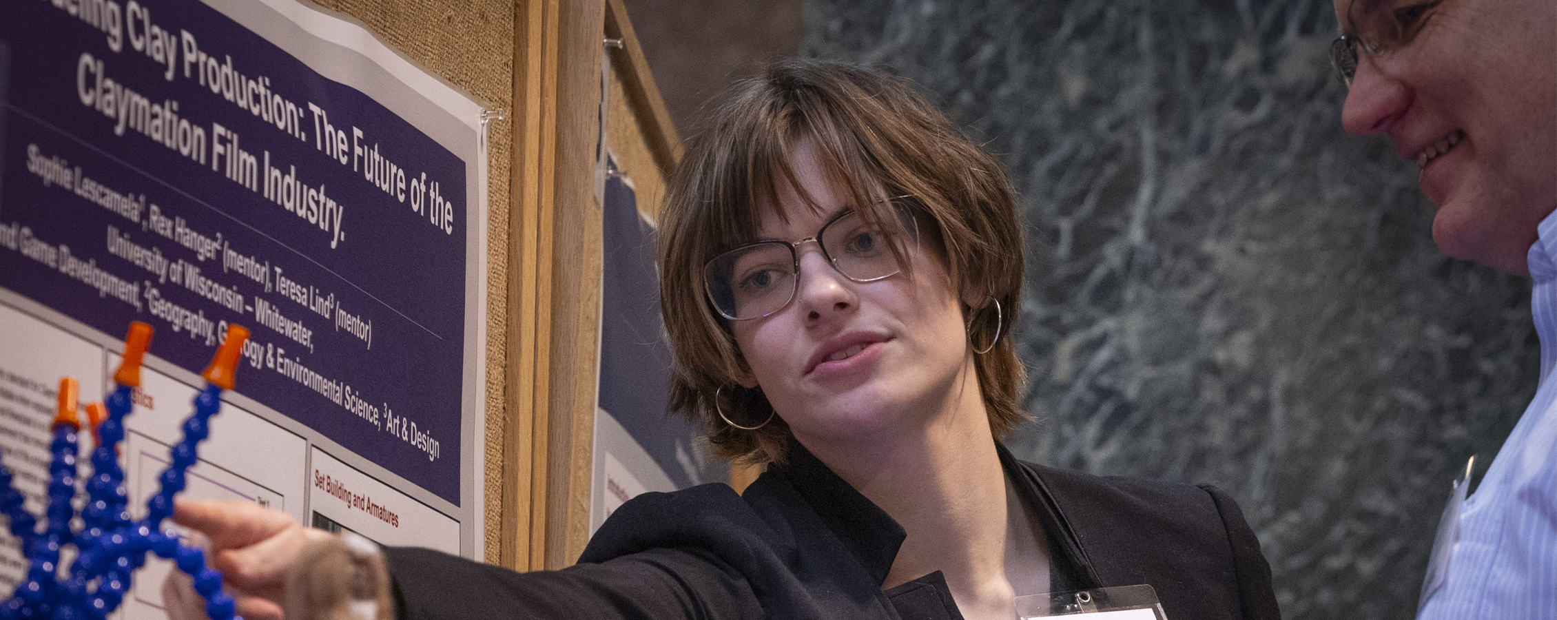 tudent talking to another person about undergraduate research findings.