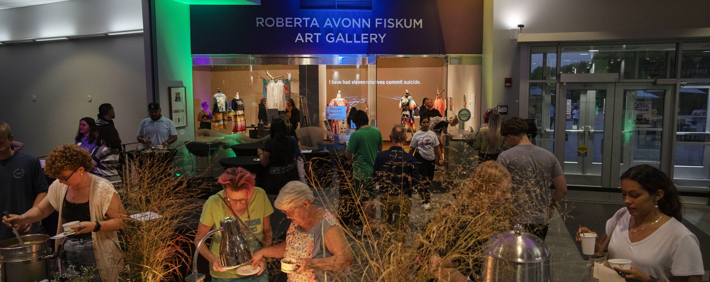 A crowd is gathered outside of Roberta's Art Gallery with coloring lighting in the background.