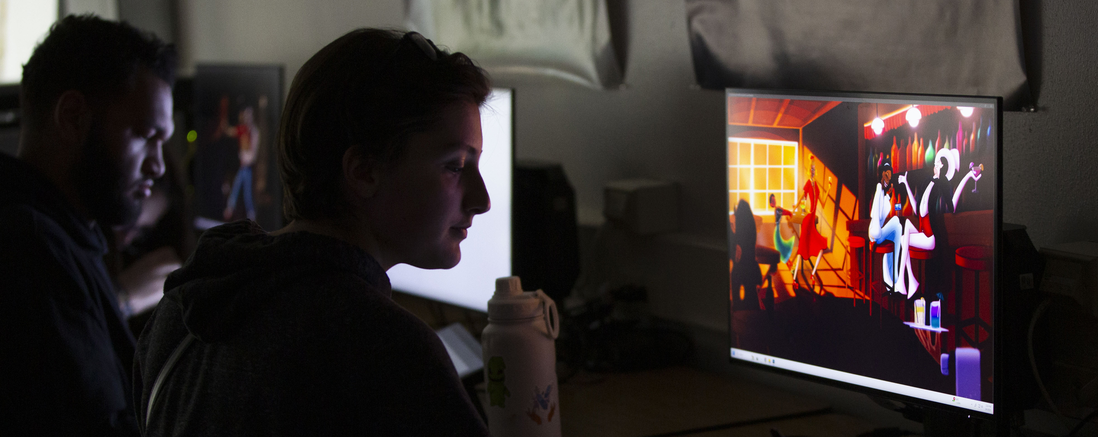 A person sits in front of a computer with colorful graphics.