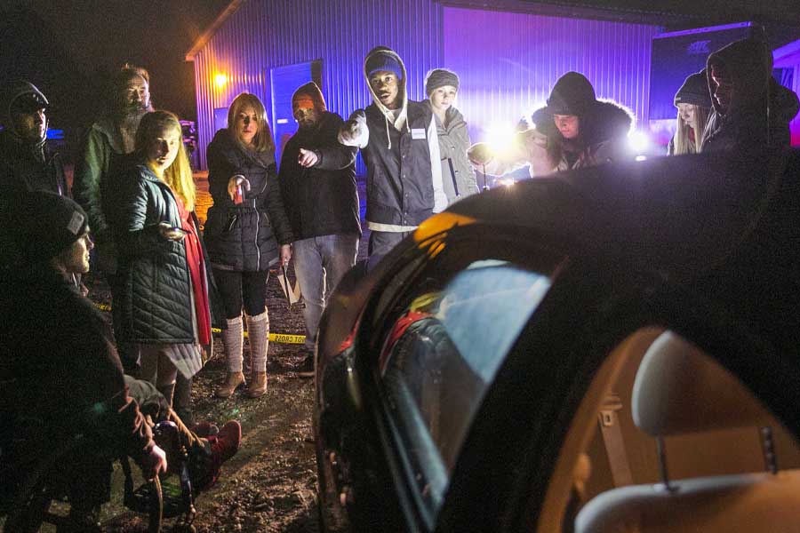 Students investigate near a car at nighttime. 