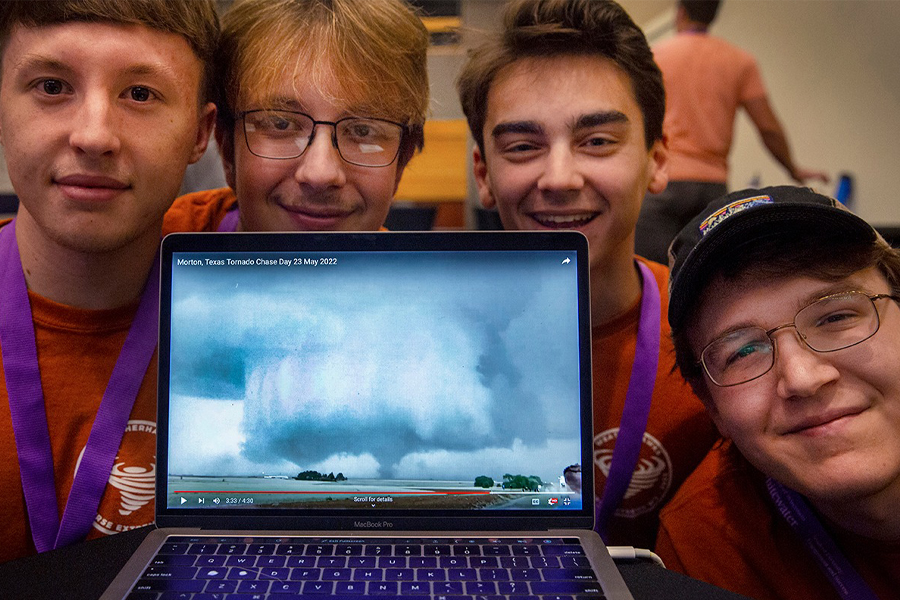 Students pose with a computer that shows stormy weather on the screen.