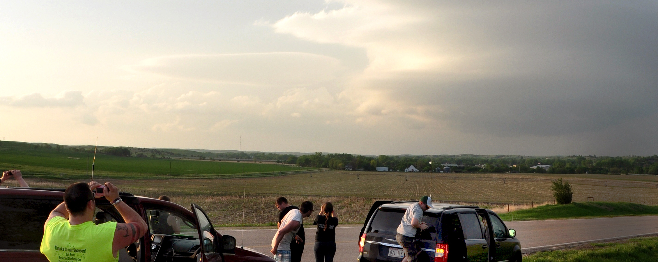 Students photograph a storm rolling in over a field.