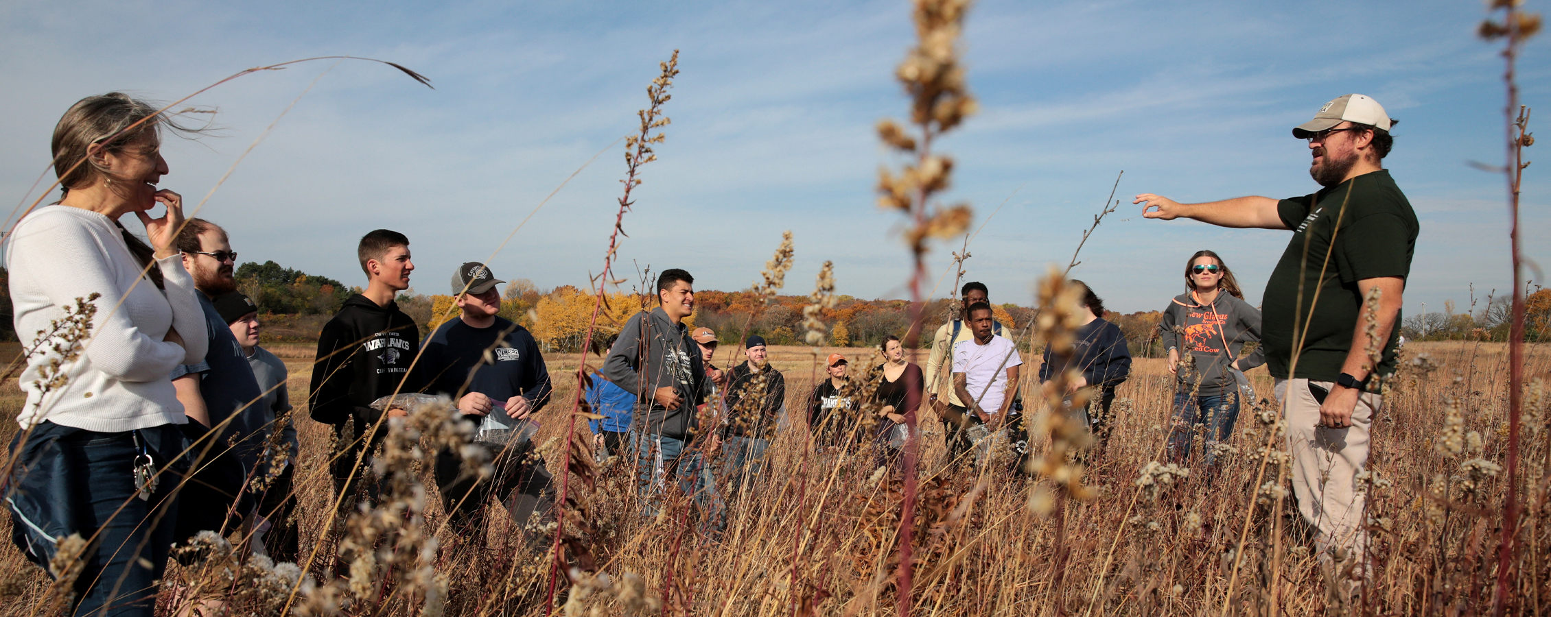 A class meets in the prairie to harvest seeds.