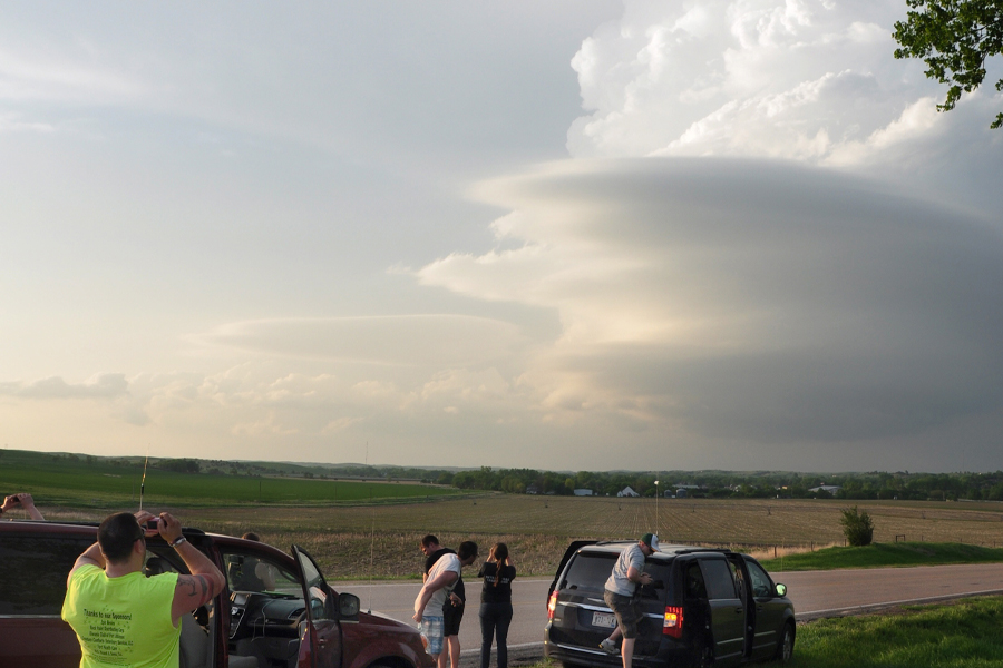 Students take pictures of a storm rolling in over a field.