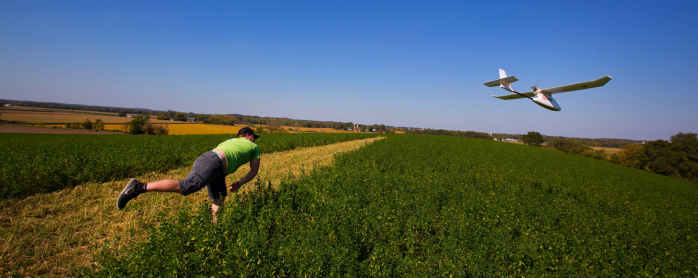 A student throws a mapping drone in a field.