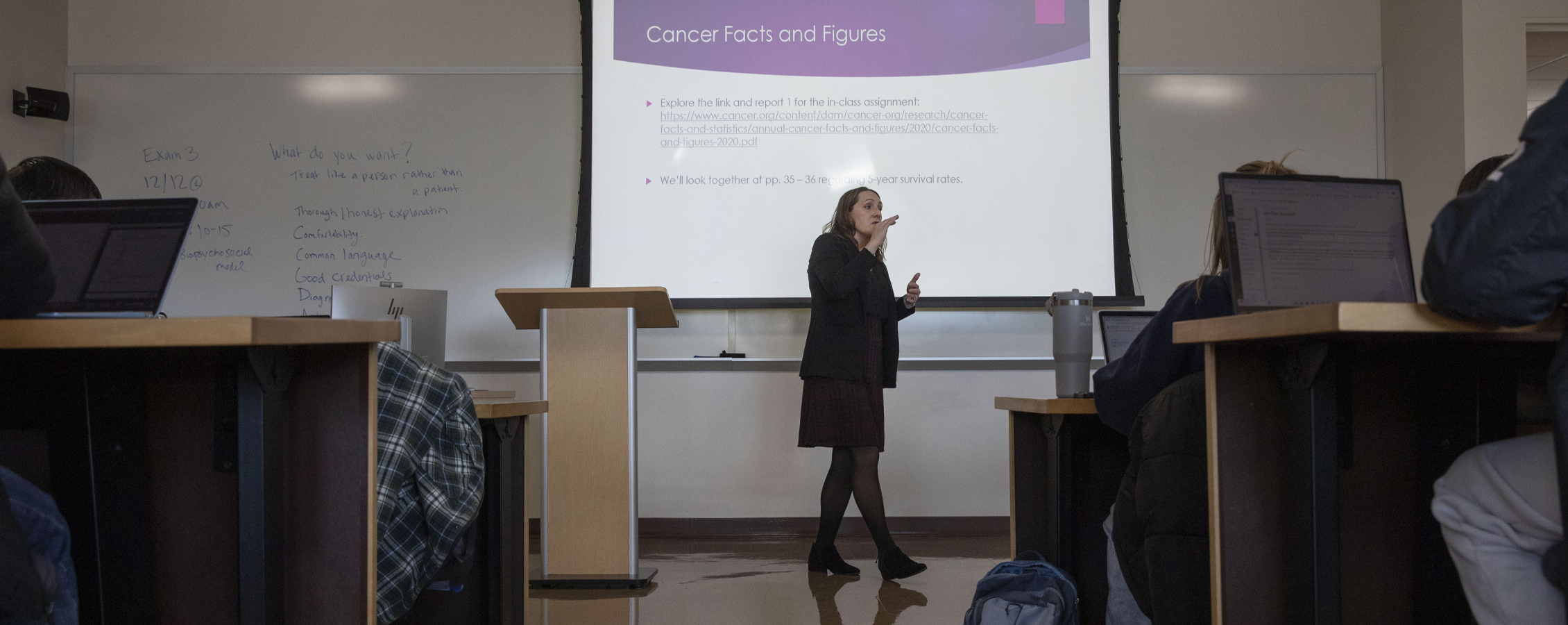 A faculty member teaches at the front of a classroom.