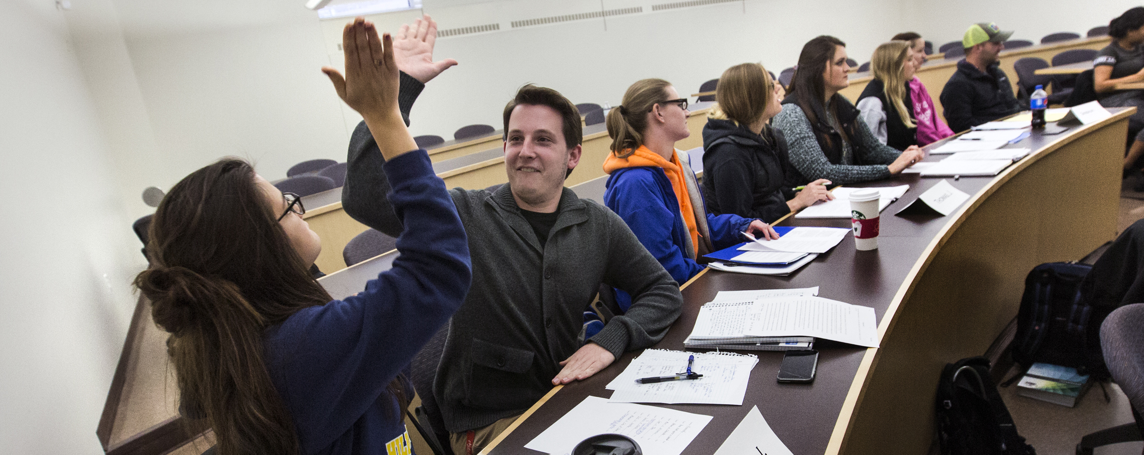 Two students high five in a classroom.