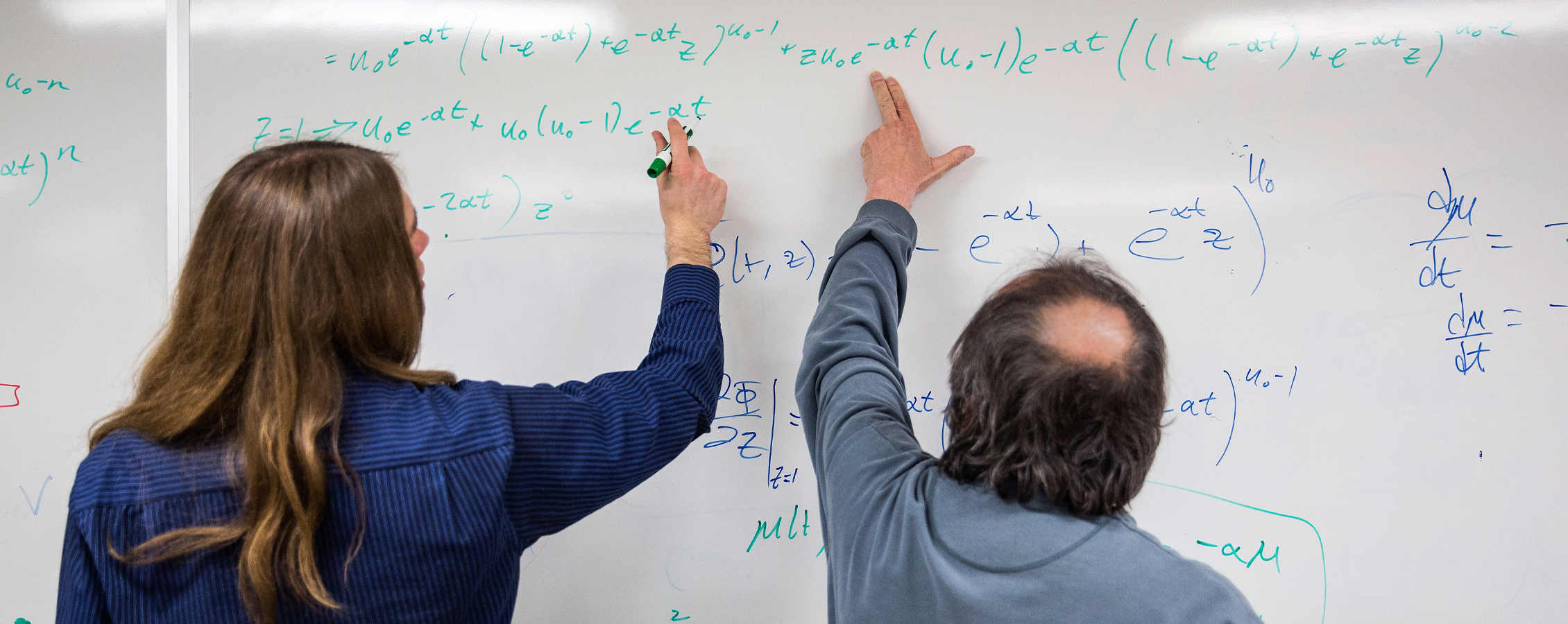 Mathematics student and instructor work on whiteboard