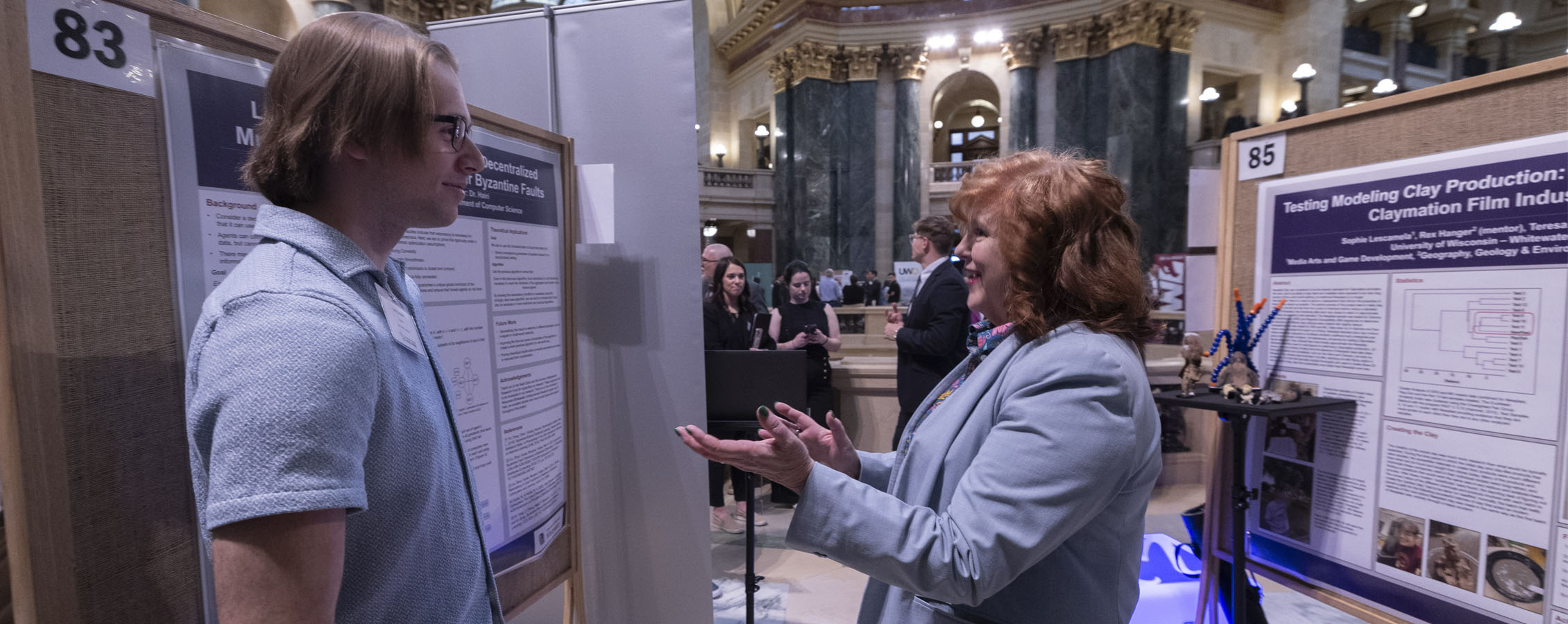 Student talking to person about undergraduate research inside the state capitol.