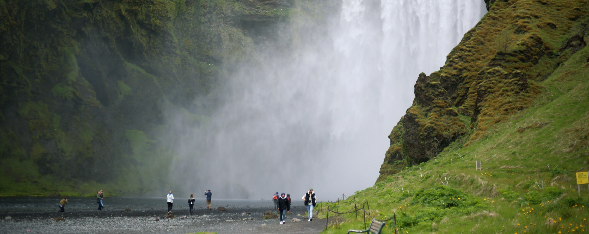 Students walk along a path by a waterfall.