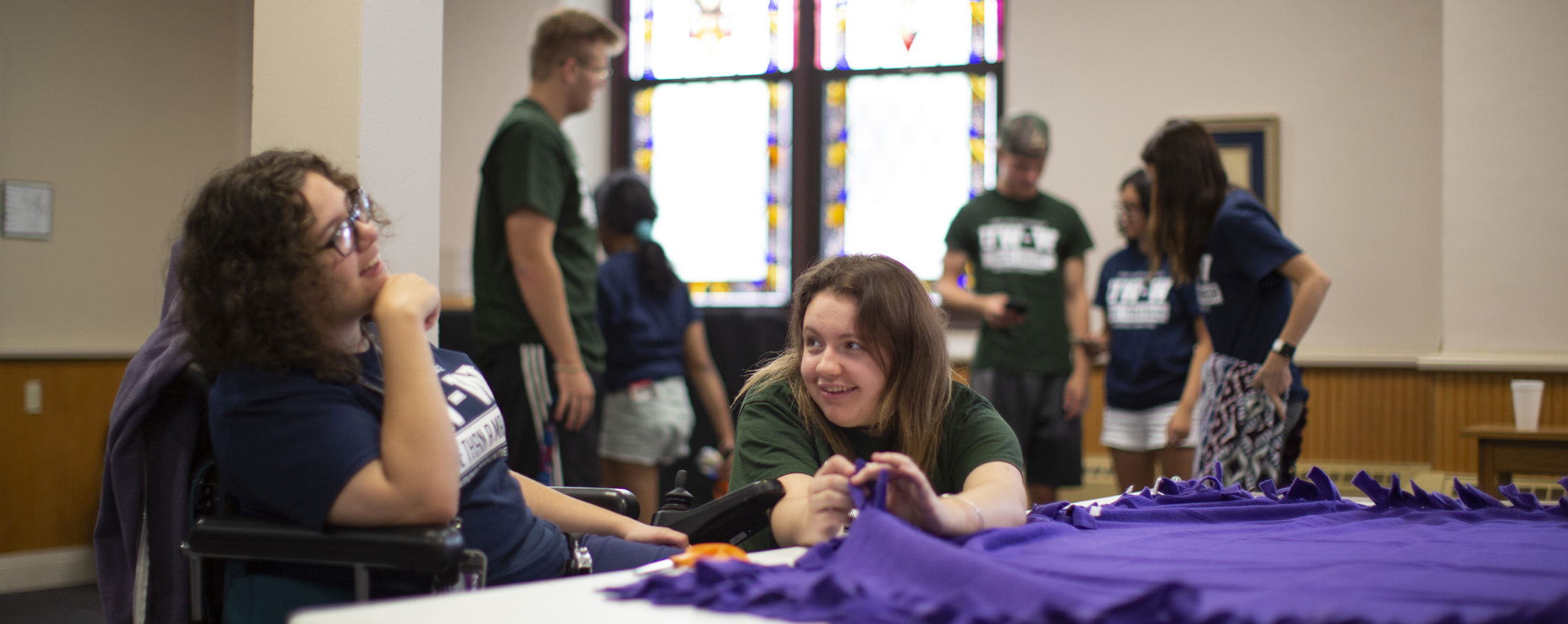 Two students make a purple blanket as they participate in community events.