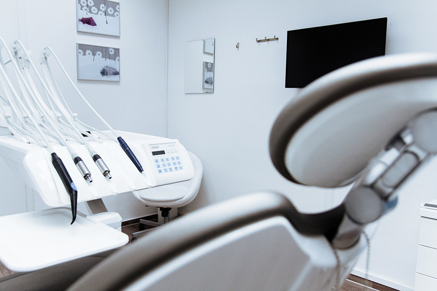 A dentist chair with dentistry tools next to it.