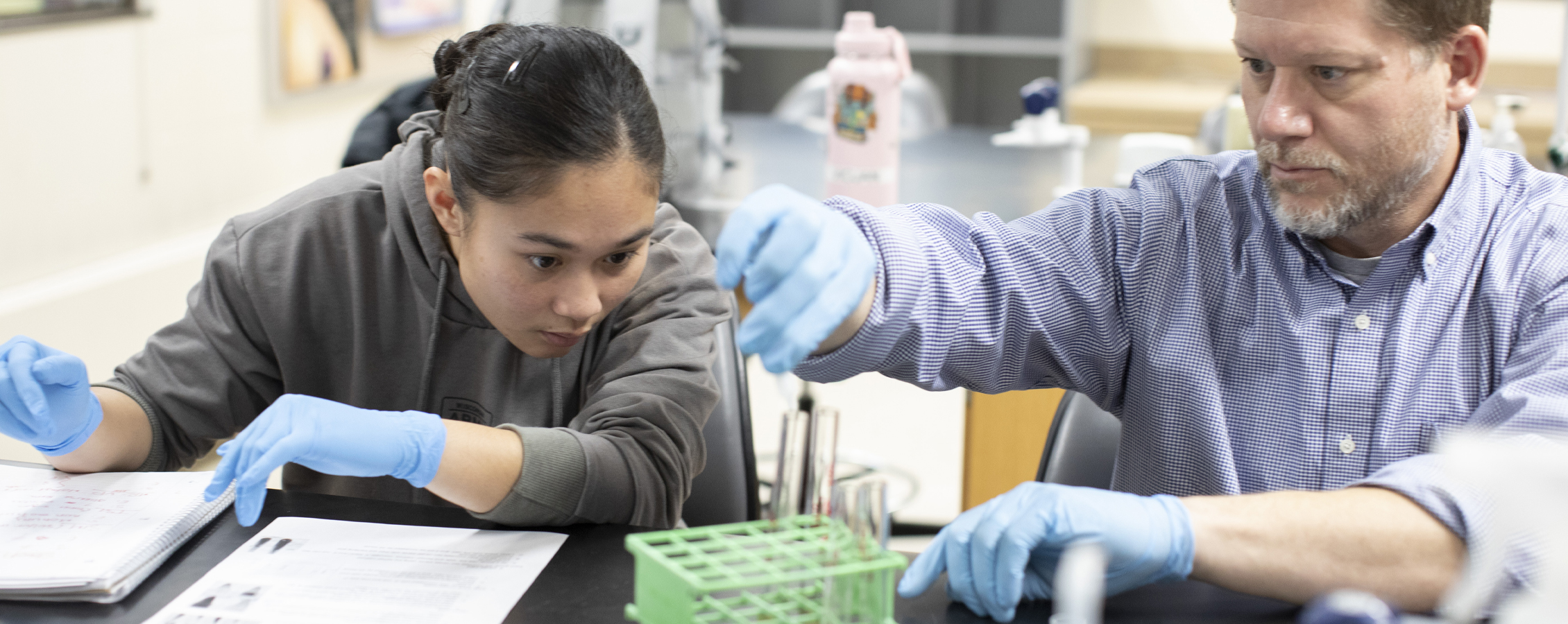 A student works in a lab with a faculty member.